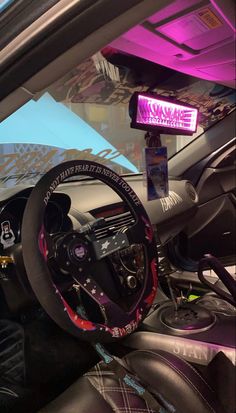 the interior of a car is decorated with pink and black accessories, including a steering wheel