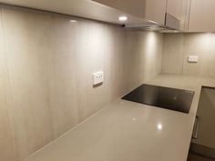 an empty kitchen with white counter tops and stainless steel stove top oven hood in the corner