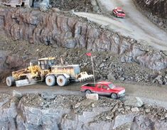 two trucks are parked on the side of a mountain