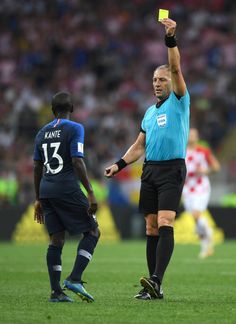 referee showing yellow card to man on soccer field