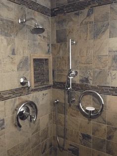 a walk in shower sitting next to a tiled wall with two faucets on each side