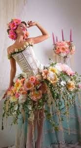 a woman in a corset with flowers on her head and candles behind her