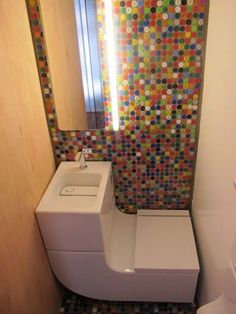 a bathroom with a toilet, sink and colorful tiles on the wall behind the mirror