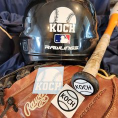 a baseball bat, glove and helmet sitting on top of a bag with stickers