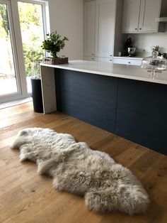 a large white sheepskin rug sitting on top of a hard wood floor in a kitchen