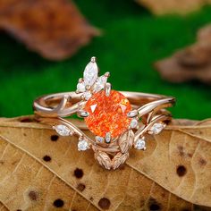 an orange diamond ring sitting on top of a leaf