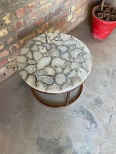 a white marble top coffee table sitting next to a brick wall and potted plant