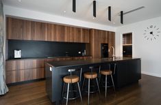 a kitchen with an island and bar stools in front of the counter top that has two clocks on it