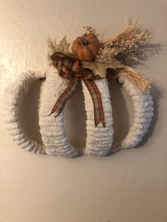 a knitted wreath hanging on the wall next to a pumpkin and cornucre