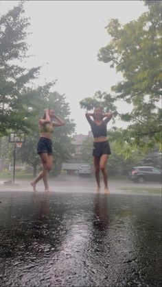 two young women are dancing in the rain