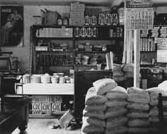 an old black and white photo of a store with lots of bags on the counter