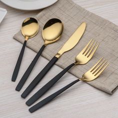 four forks, two spoons and one knife are sitting on a napkin next to a plate