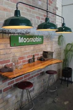 three green lights hanging from the ceiling above a wooden table with two stools underneath it