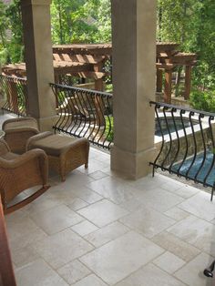 two wicker chairs sitting on top of a patio next to a pool