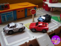 two toy cars are parked on the road in front of a stop sign and store