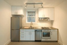 an empty kitchen with stainless steel appliances and white cabinets