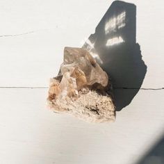 a rock sitting on top of a white wall next to a shadow from a window