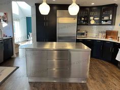 a large kitchen with stainless steel appliances and black cabinetry, along with hardwood flooring