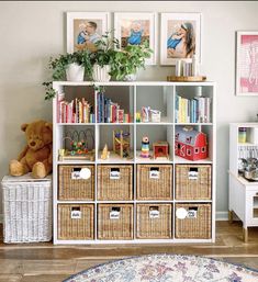 a white bookcase filled with lots of books next to a teddy bear and potted plant