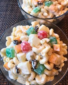 two clear bowls filled with pasta salad on top of a table