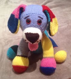 a knitted dog sitting on top of a bed