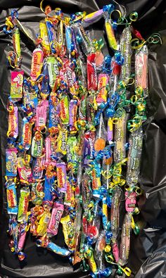 a pile of candy on top of a black plastic bag with ribbons and bows around it