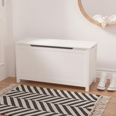 a white chest sitting on top of a wooden floor next to a rug and shoes