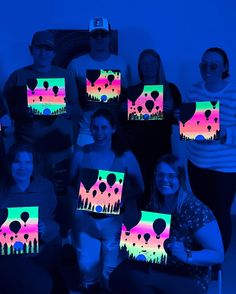 a group of people holding up paintings in the shape of balloons and trees at night