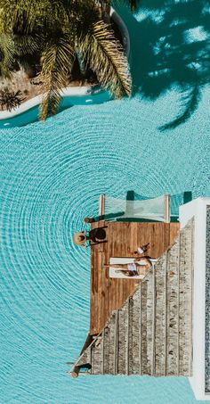 an aerial view of a wooden dock in the middle of blue water with palm trees