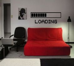 a red couch sitting in front of a laptop computer on top of a white desk