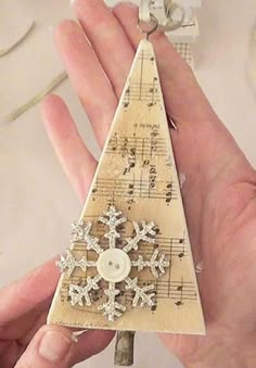 a hand holding a small wooden christmas tree ornament with musical notes and snowflakes