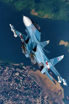 a fighter jet flying through the air over a city and lake in an aerial view