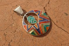 This beautiful Pendant with Coca Leaf is handmade by the beautiful Quechua people of the Peruvian Andes. It is made by 950 silver and gemstones of the region ( Lapiz Lazuli, Crystacola, spondyllus) weight : 10.4 gr diameter : 3.3 cm height with hook : 4.8 cm It is handmade in 950 silver with inlaid stone and shell by a local family of jewelry artesians. Colorful Bohemian Gemstone Jewelry, Southwestern Style Multicolor Round Jewelry, Artisan Multicolor Jewelry With Inlay, Multicolor Spiritual Jewelry With Inlay, Nickel-free Multicolor Round Pendant Jewelry, Spiritual Multicolor Inlay Jewelry, Southwestern Silver Heart-shaped Jewelry, Bohemian Nickel-free Heart Pendant Jewelry, Multicolor Southwestern Nickel-free Earrings