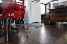 two red chairs sitting on top of a wooden floor next to a dresser and piano