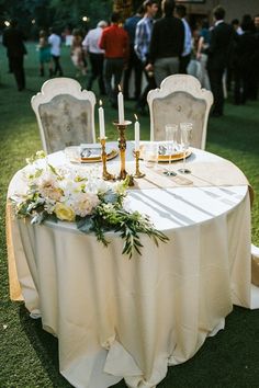 the table is set with white linens and gold candles for an elegant wedding reception