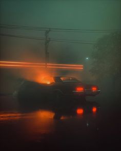 a car is driving down the road in the rain at night with its headlights on