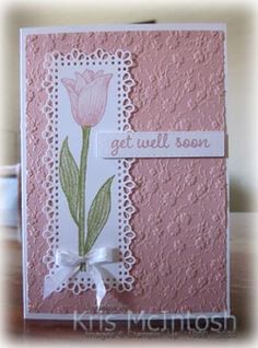 a handmade card with a pink flower on the front and white border around it