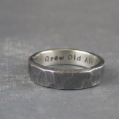 a wedding band with the words grow old all over it, on a gray surface