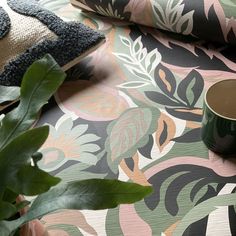 a green plant sitting on top of a table next to a cup