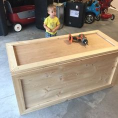 a young boy standing in front of a wooden box with tools on the table top