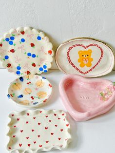 five different shaped plates and trays on a white surface with a teddy bear painted on them