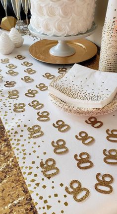 a table topped with a white cake covered in gold confetti