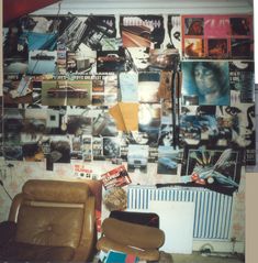 a wall covered in photos and pictures next to a radiator with a chair