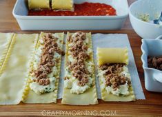 some ravioli with meat and cheese are on a wooden table next to bowls of condiments