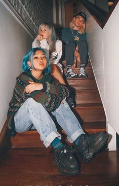 three young women sitting on the stairs with their arms around each other and looking up