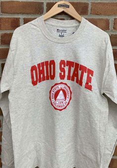 Champion Ohio State Buckeyes Oatmeal Arch Mascot Long Sleeve T Shirt - 14755698 Pre-shrunk Crew Neck Varsity T-shirt, Casual Crew T-shirt For Fan Gear, Casual Crew Neck T-shirt For Fans, Casual Crew T-shirt For Game Day, Casual Gray Top For Game Day, Athletic Heather Varsity Cotton Top, Fabric Outfits, University Tshirt, Irish Pride