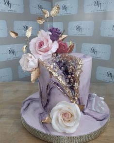 there is a purple cake with flowers on the top and gold leaf decorations around it