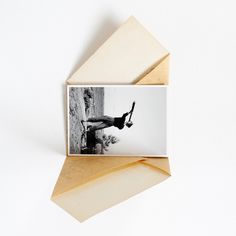 an open envelope with a photograph of a man hanging from it's side, on top of a piece of wood