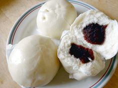 three buns on a plate with jam in the middle