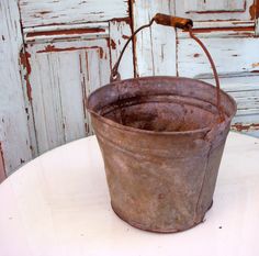 an old metal bucket sitting on top of a white table